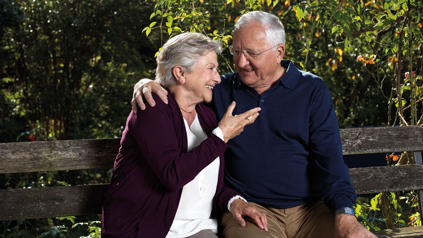 Eine Seniorin und ein Senior sitzen auf einer Bank und schwatzen miteinander