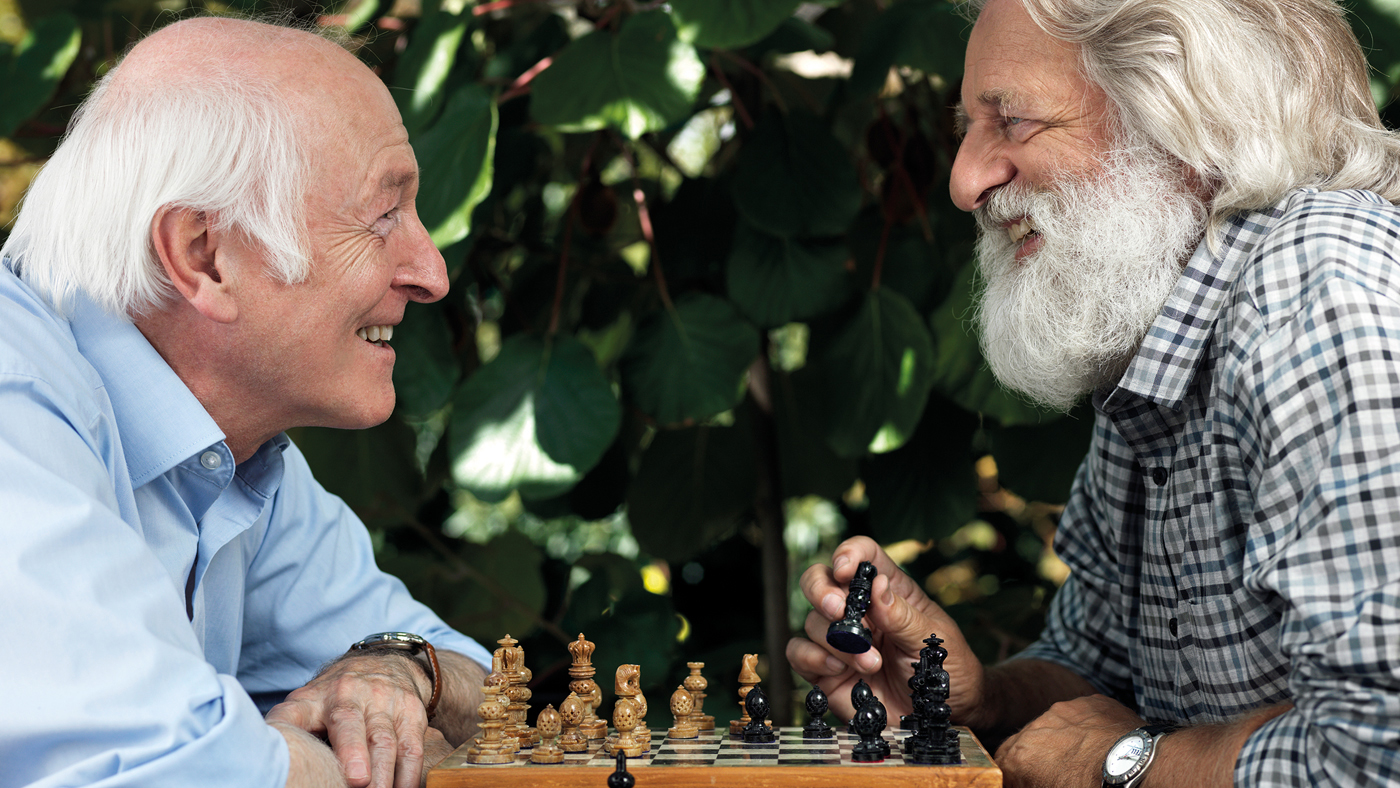 Zwei Senioren spielen Schach und lachen dabei
